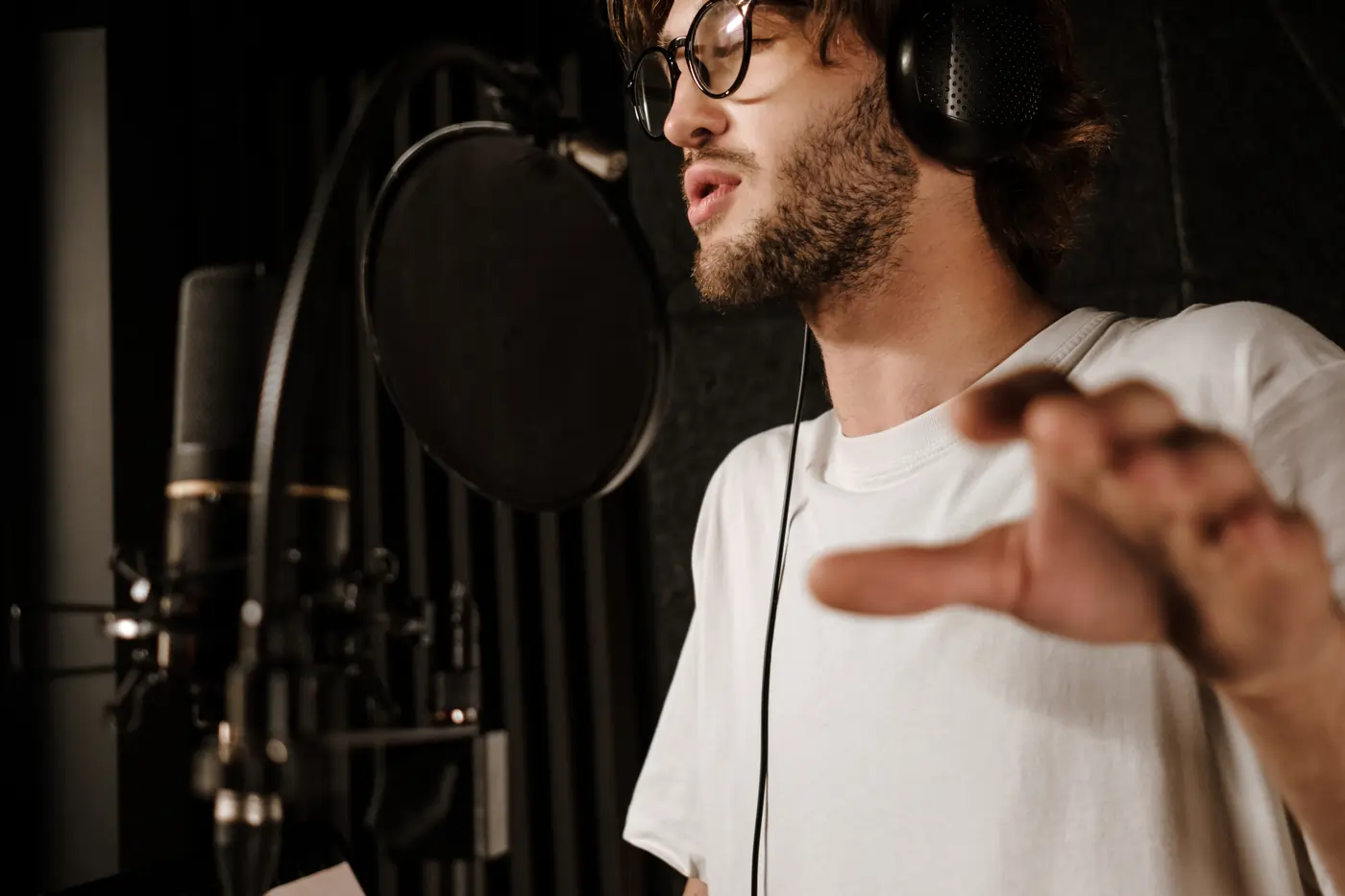 Un hombre con auriculares canta con un micrófono profesional en un estudio